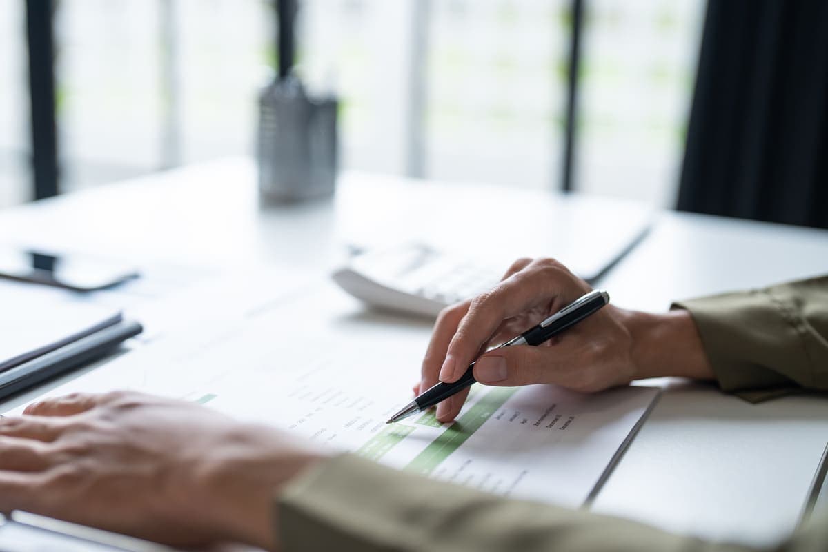 Hand with a pen reviewing a financial statement