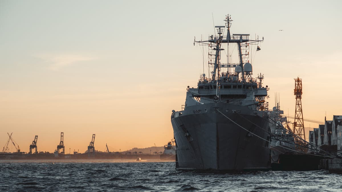 Navy ship docked in a harbor at sunset